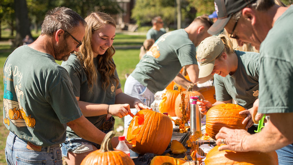 People having a good time carving pumpkins.