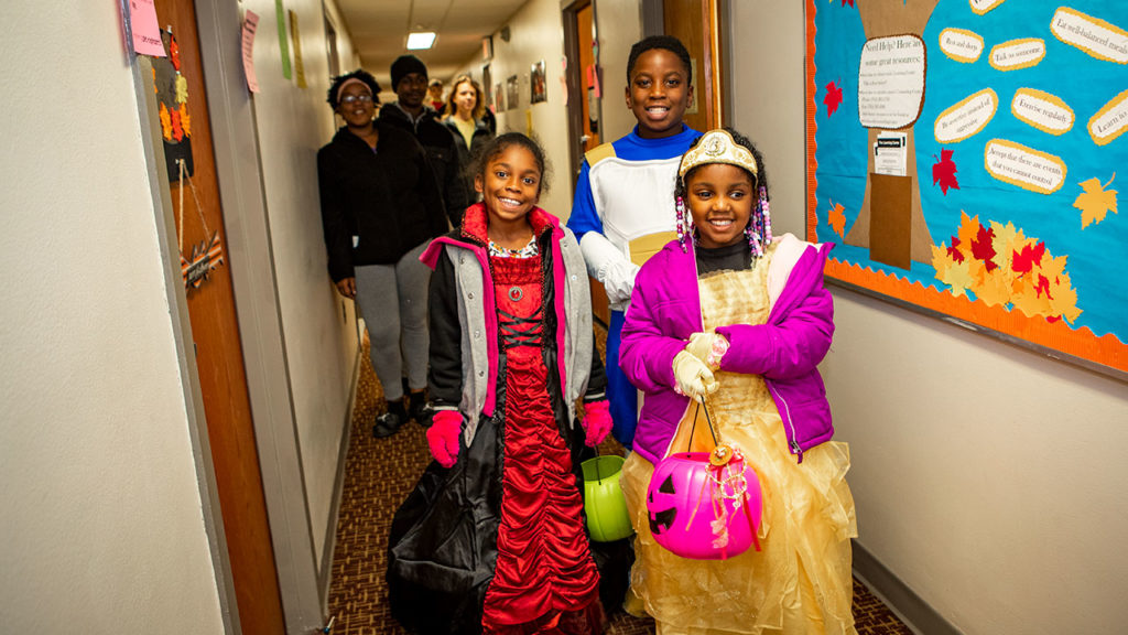 Children wearing Halloween costumes and smiling.