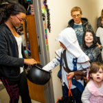 Student passing out Halloween candy to children.