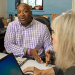 Man seated and speaking with a woman