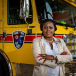 Woman with arms cross standing in front of firetruck