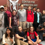Group of graduate students pose in front of the CICS sign