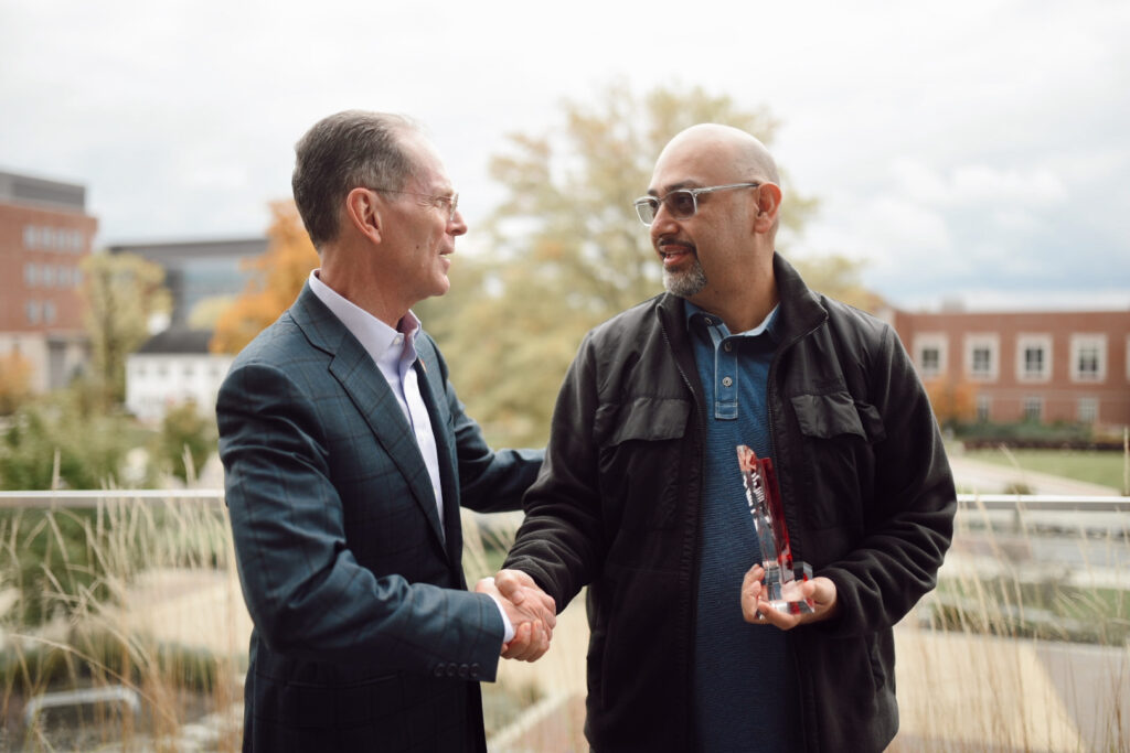 Jerry Walker shakes President Geoffrey Mearns' hand and accepts an award