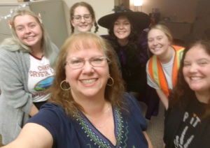 From left to right of the image: Graduate practicum student, Mikayla Yohe, Disability Services' administrative coordinator Sharon Harper, undergraduate desk staff student Catherine Hearn, Graduate assistant Olivia Vecchiolli, Assistant Director Jordan Grammas, and Director Courtney Jarrett are seen posing for a Halloween photo. Sharon is holding the phone at an upward angle to take a selfie. Everyone is dressed in costume for Halloween. For more details on individual's halloween costumes please email dsd@bsu.edu.