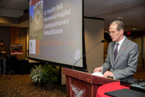 President Mearns stands at a podium beside a screen that reveals this year's award winners